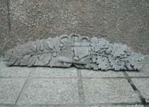 An arch, made when he was 13 years old in school, 
represents strength, glory, and knowledge.
From the left, acorns and oak leaves represent strength; books represent knowledge; laurel represents glory