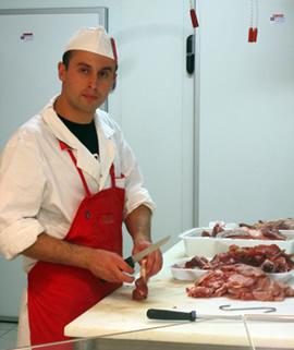 Ervis Chano stands behind the butcher counter at the local grocery store, Coal.