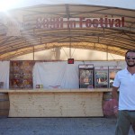 Director of the Festival in Cagli, Luca Ascani, stands in front of a beer kiosk.