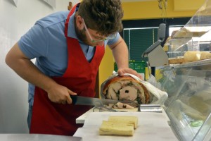 Matteo Grossi, who helped begin Famiglia Grossi Artisti Salumieri, cuts fresh slices of ham for a customer’s sandwich in the lunch hours.