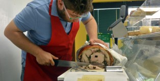 Matteo Grossi, who helped begin Famiglia Grossi Artisti Salumieri, cuts fresh slices of ham for a customer’s sandwich in the lunch hours.