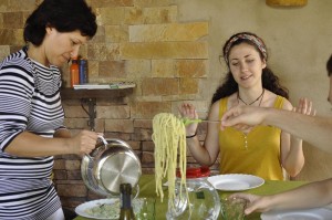 A large plate of pesto pasta is the centerpiece and is served to all.