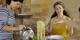 A large plate of pesto pasta is the centerpiece and is served to all.