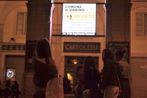 While most university students are home for the weekend, younger students spend their night in the piazza taking a moment to read the alcohol sign.