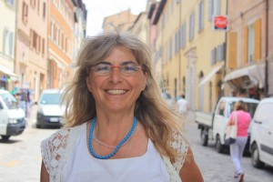 Maria Giovanna Luminati stands under the arch entering Urbino, proudly welcoming guests and visitors.