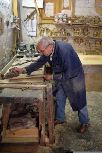 Domenico hunched over a piece of wood in the middle of shaving the rough edges. 